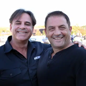 two smiling men in black shirts posing for the camera