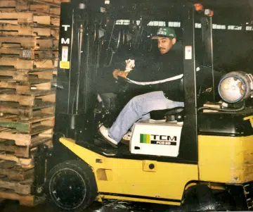 a photo of a man riding a yellow forklift inside a warehouse