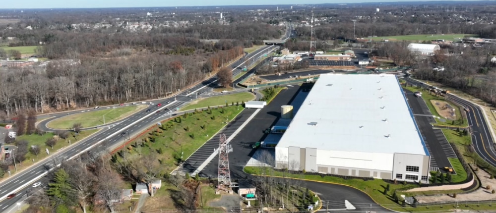 An aerial view of a spacious warehouse adjacent to a busy highway