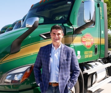 a man standing in front of a green truck parked in a parking lot