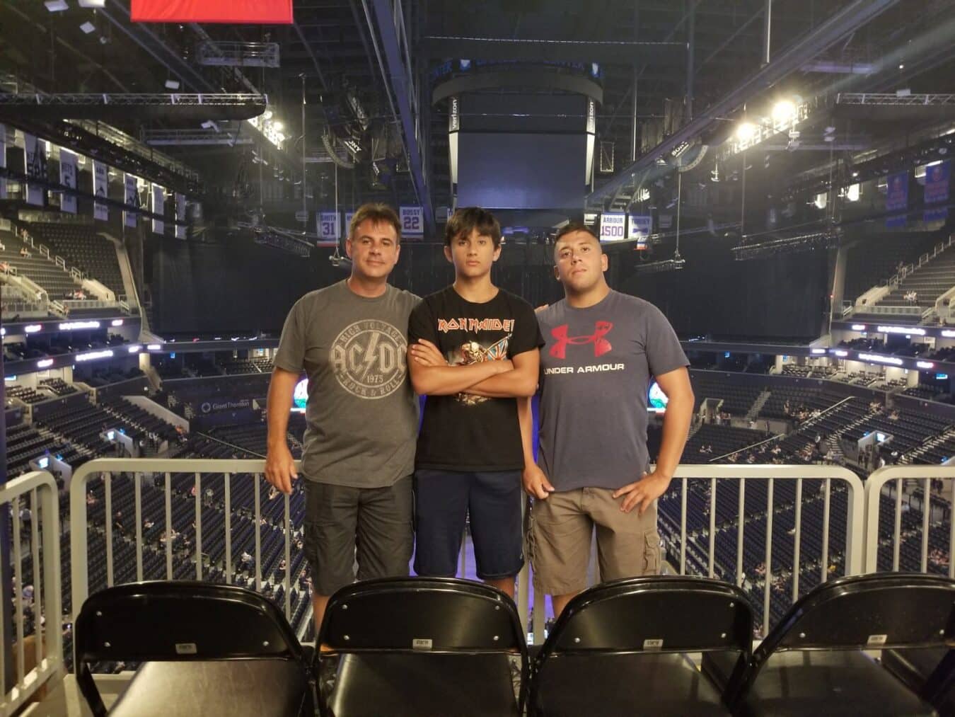 three men standing by their seats at a concert