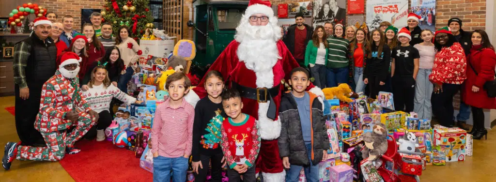 Group photo of people standing around toys